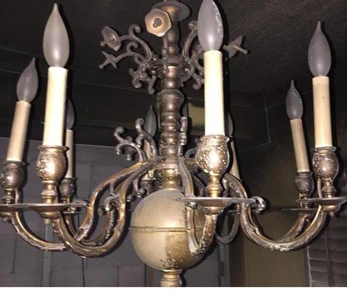 Chandelier after a fire with soot and burn damage