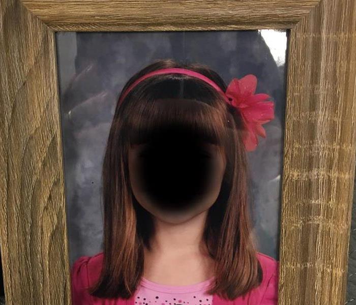 Picture frame of girl with long brown hair whose face has been blurred out for privacy reasons showing after fire cleaning