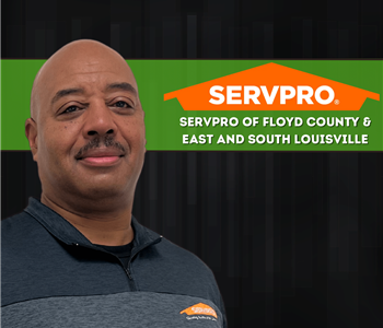 man smiling at camera wearing a SERVPRO shirt with a SERVPRO logo behind him