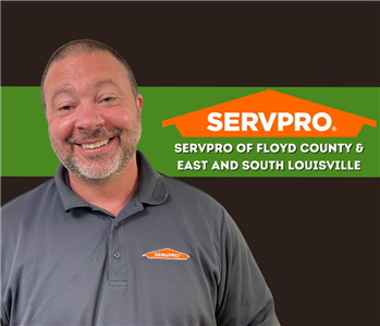 man smiling at the camera in a SERVPRO shirt on a black background